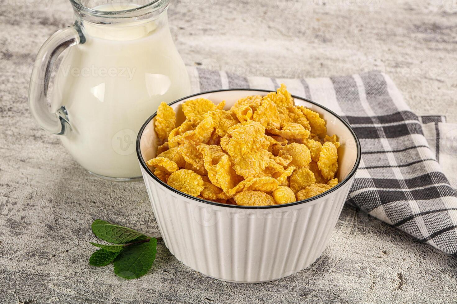 Corn flakes in a white bowl with milk on a wooden table photo