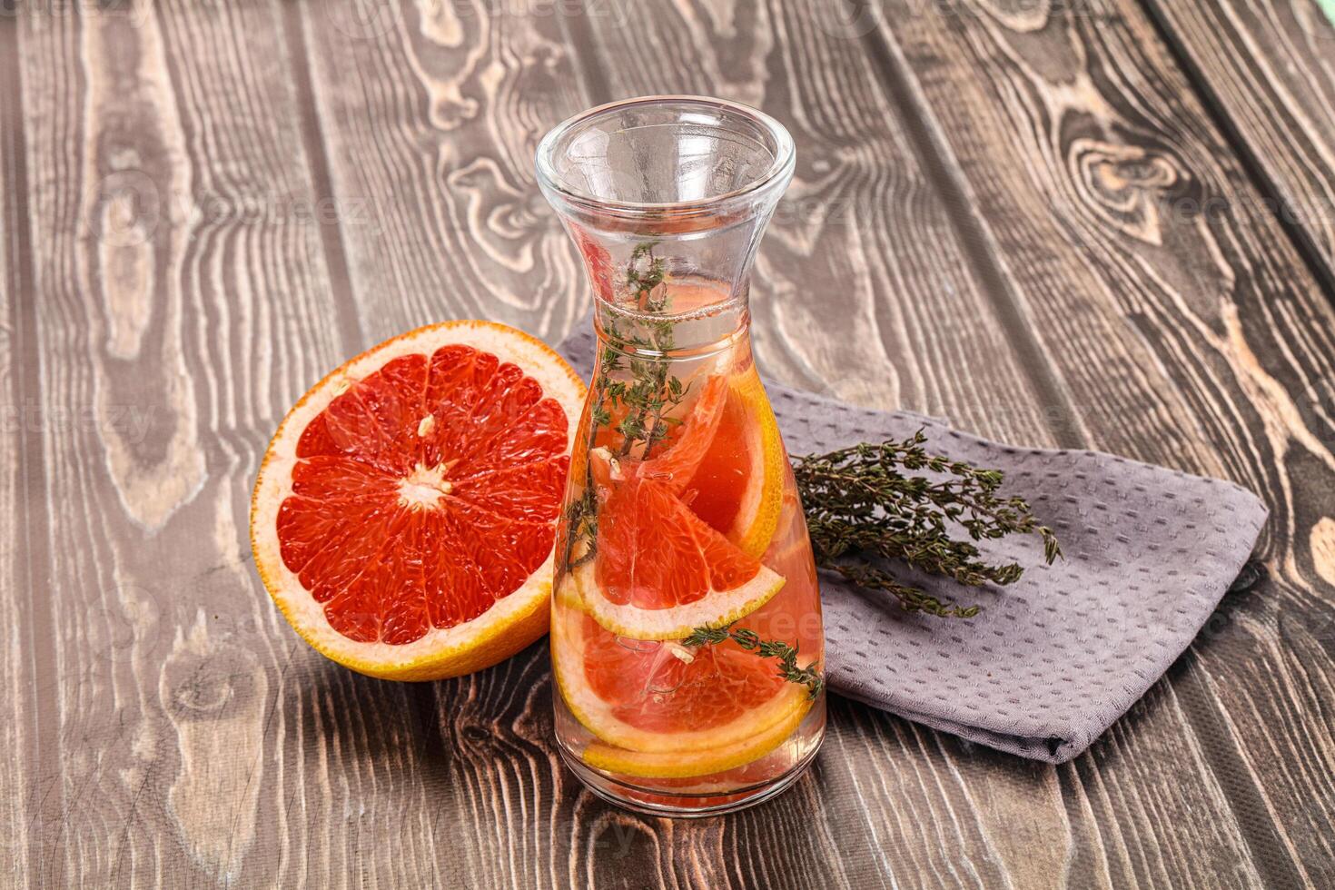 A glass pitcher with a grapefruit and herbs in it photo