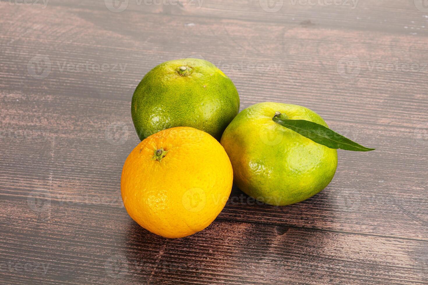 Three oranges and a lemon on a wooden table photo