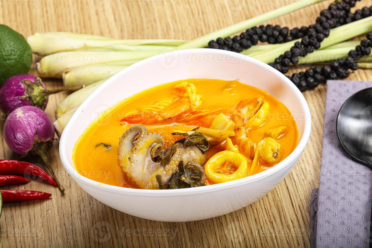 A bowl of soup with a spoon and some vegetables photo