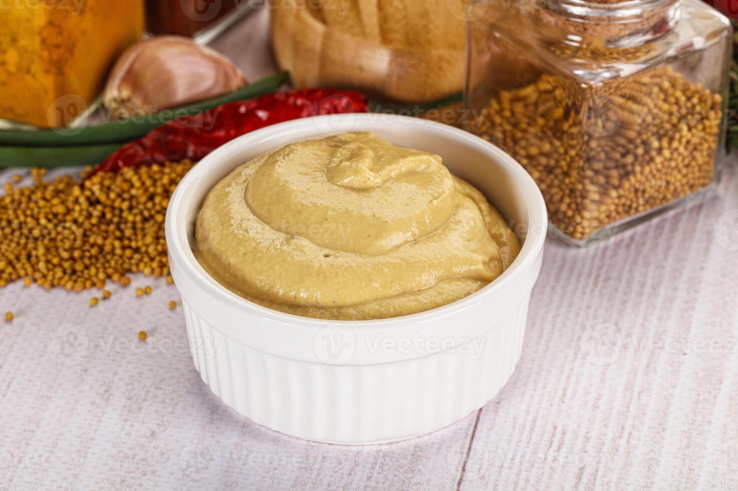 A bowl of mustard and spices on a table photo