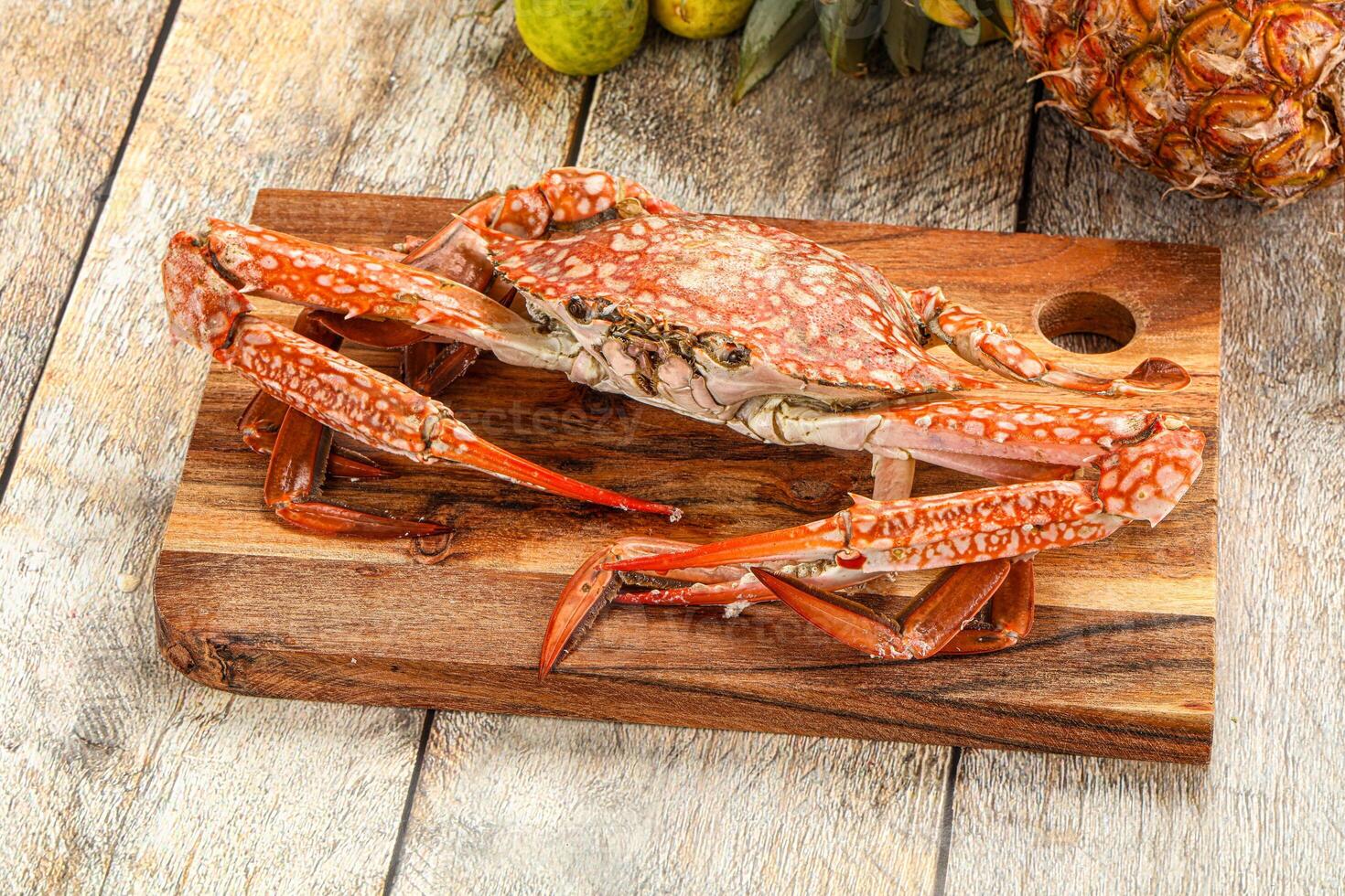 A crab on a cutting board with a pineapple and other fruit photo