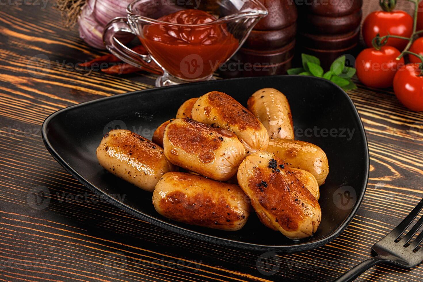 A black plate with some sausages and ketchup photo