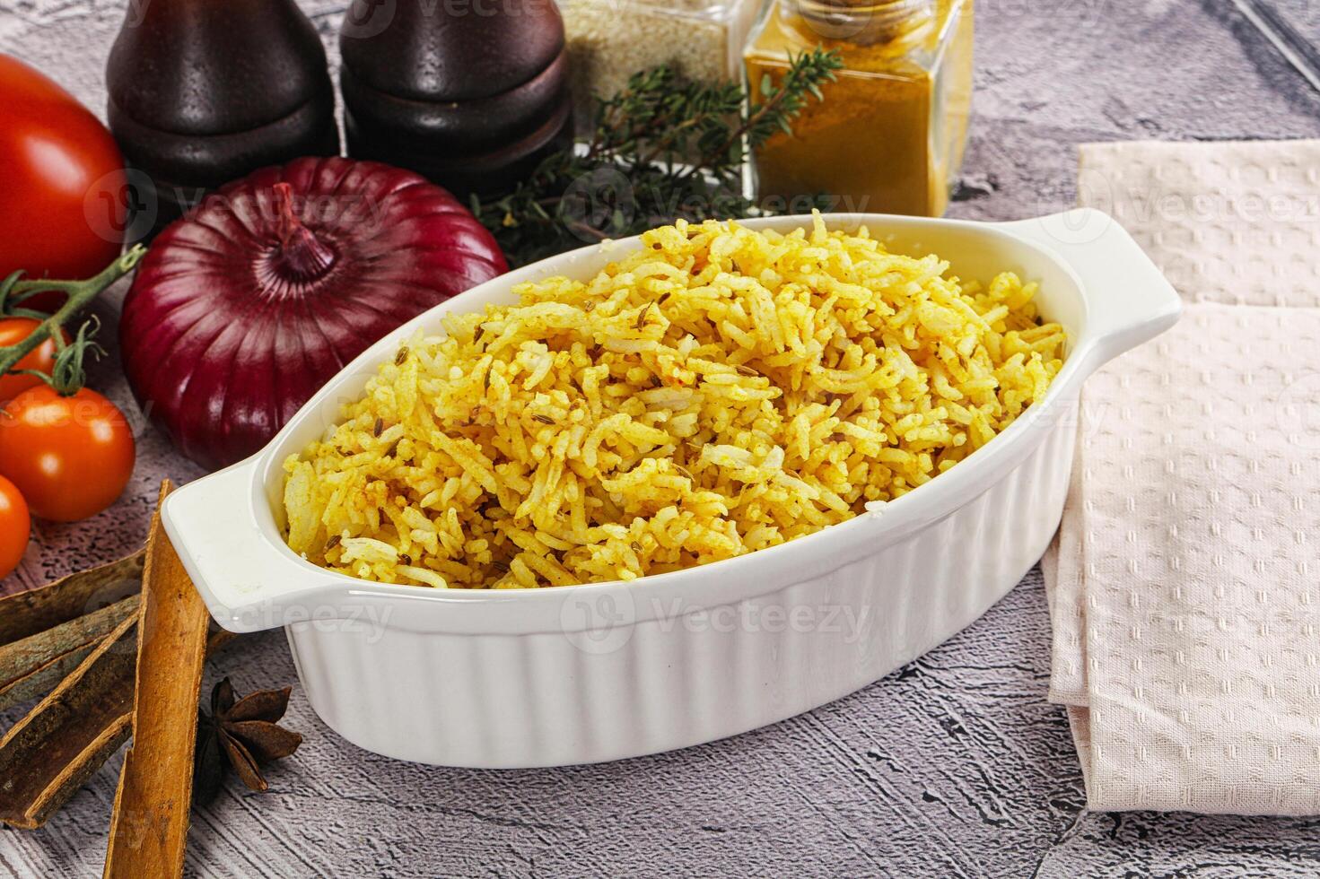 A bowl of rice with spices and vegetables on a table photo