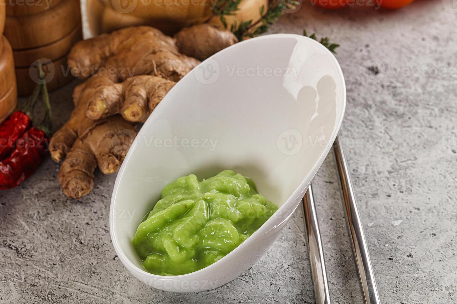 A bowl of green sauce next to a bowl of ginger photo