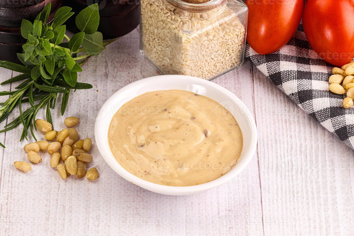 A bowl of mustard next to a bowl of tomatoes photo