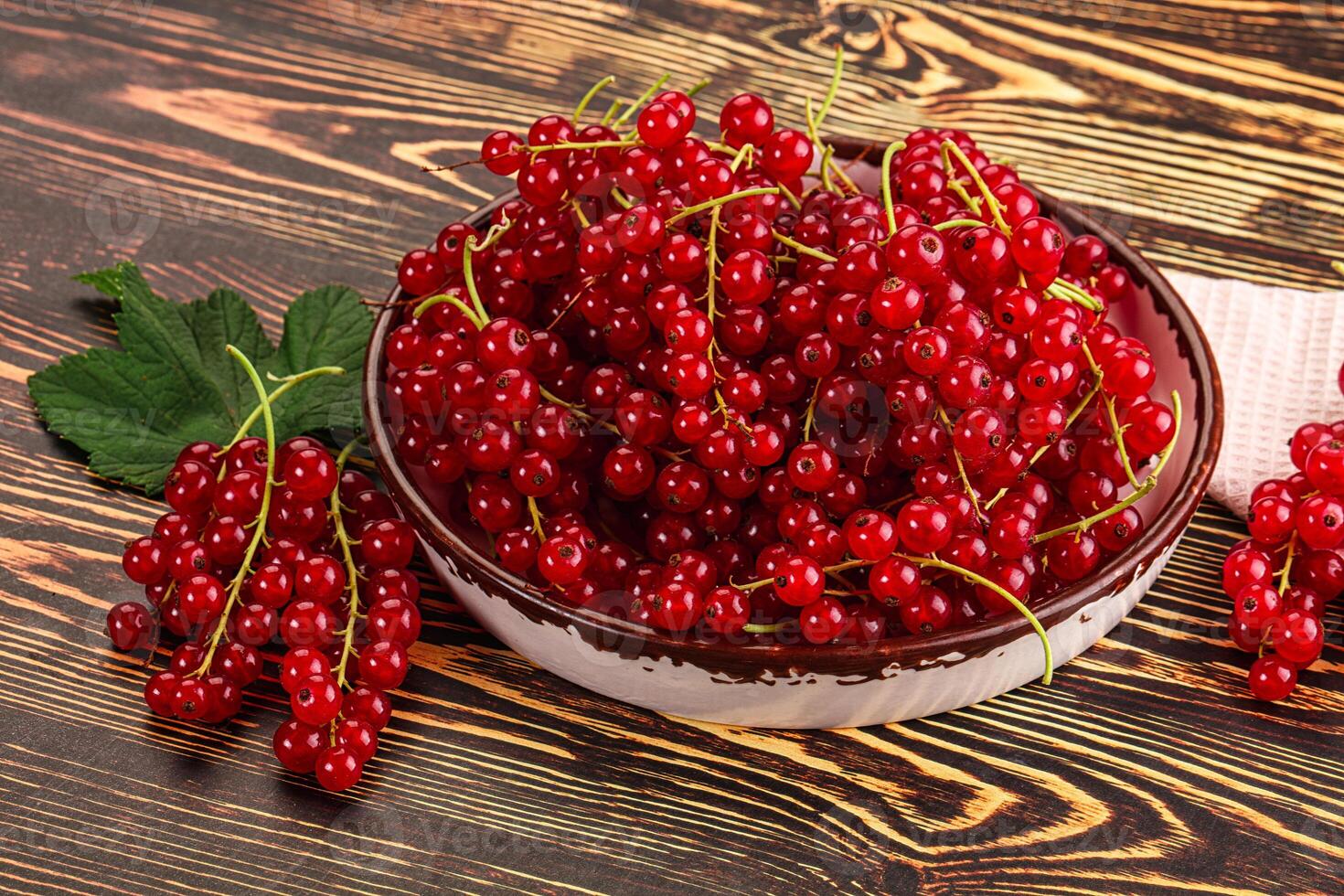 A bowl of red currants on a wooden table photo