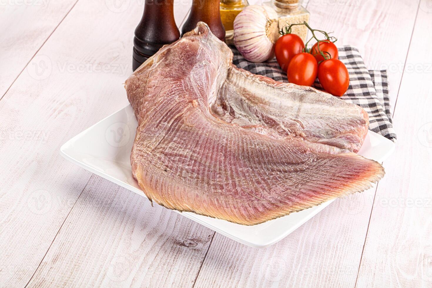 A piece of raw fish on a plate with tomatoes and other ingredients photo