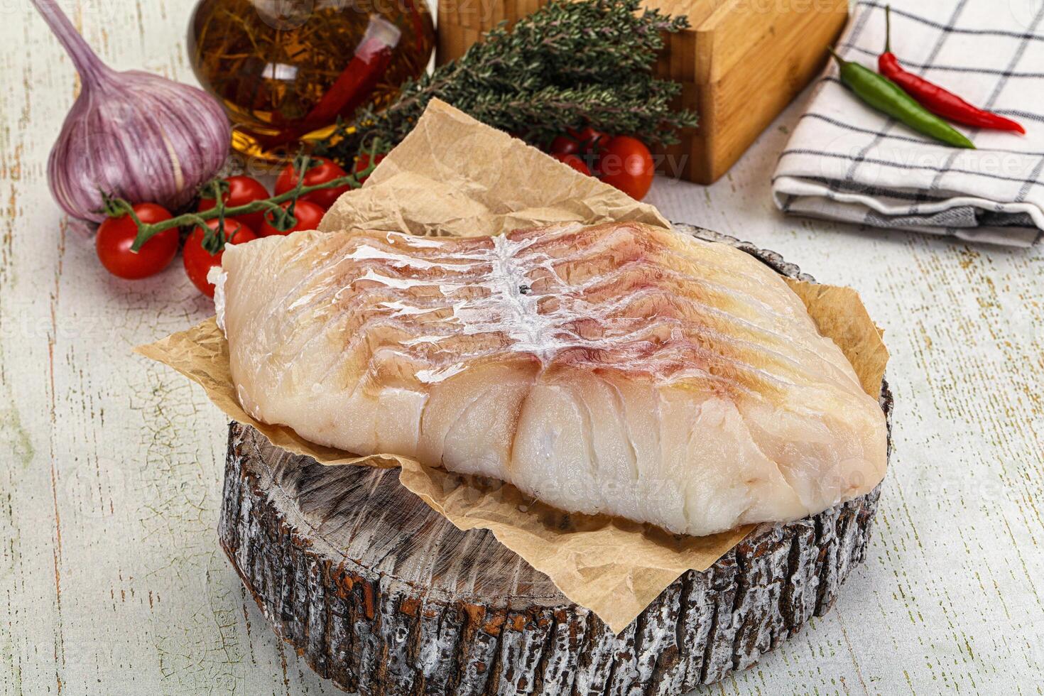 A piece of fish on a wooden table with other ingredients photo