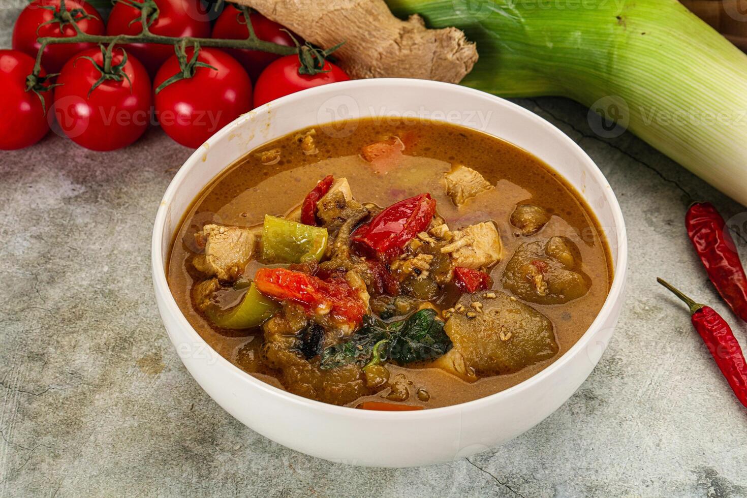 A bowl of curry with vegetables and tomatoes photo