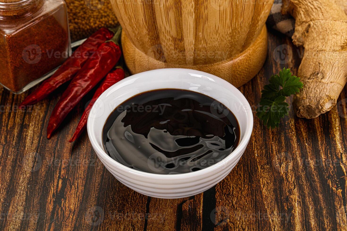 A bowl of black liquid next to spices and ginger photo