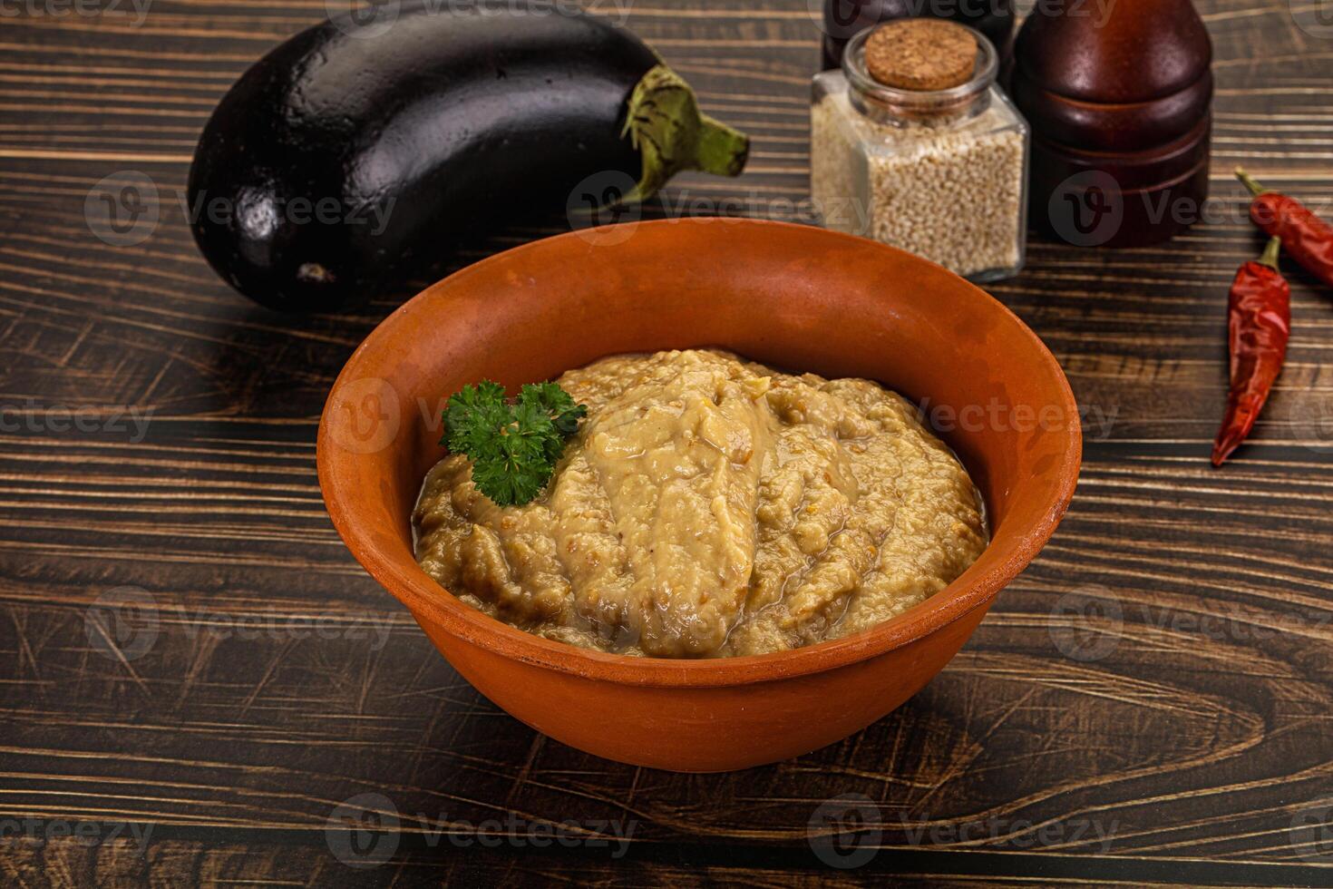 A bowl of eggplant and spices on a wooden table photo