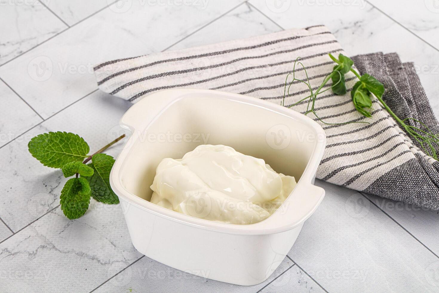 A bowl of yogurt sits on a table next to a towel photo