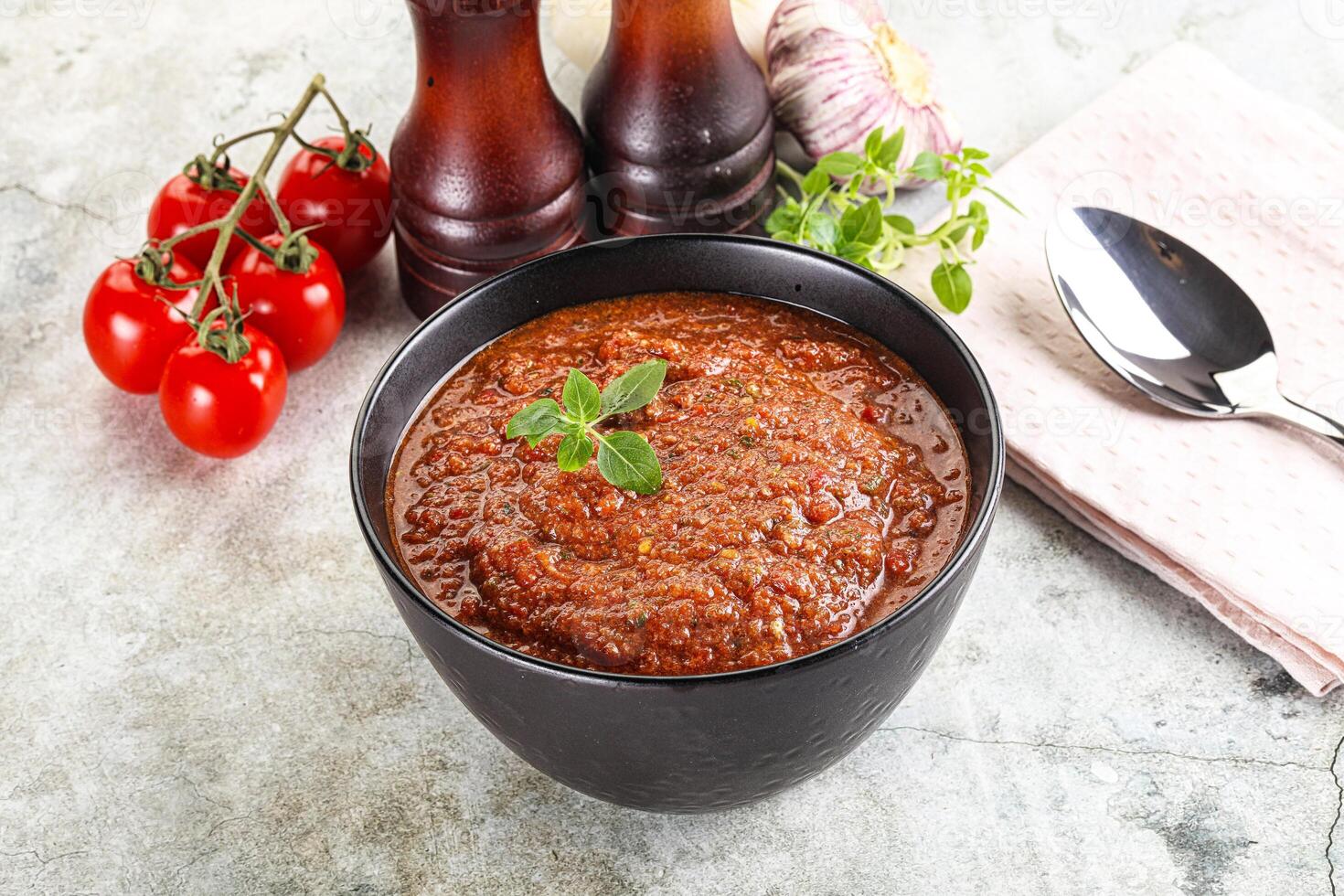 A bowl of tomato sauce with a spoon and a knife photo