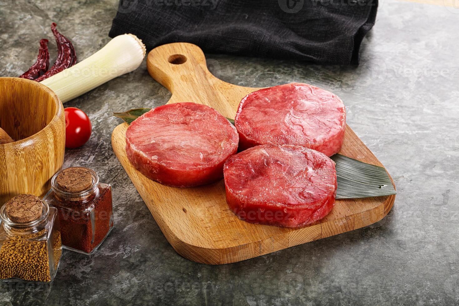 A cutting board with four steaks on it photo