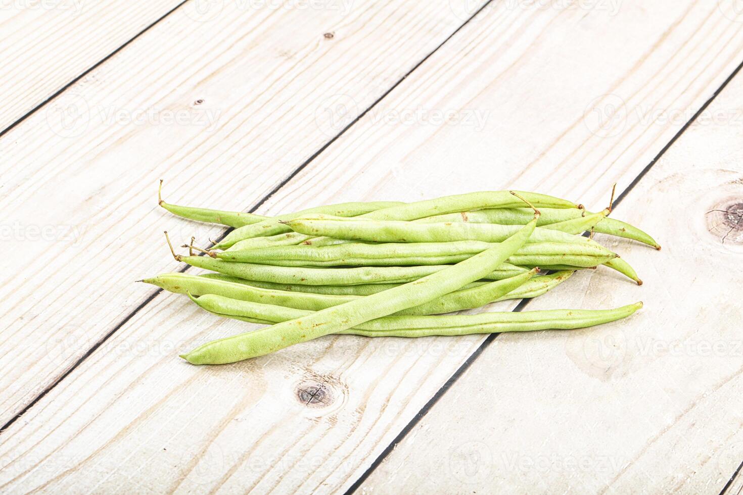 A bunch of green beans on a wooden table photo