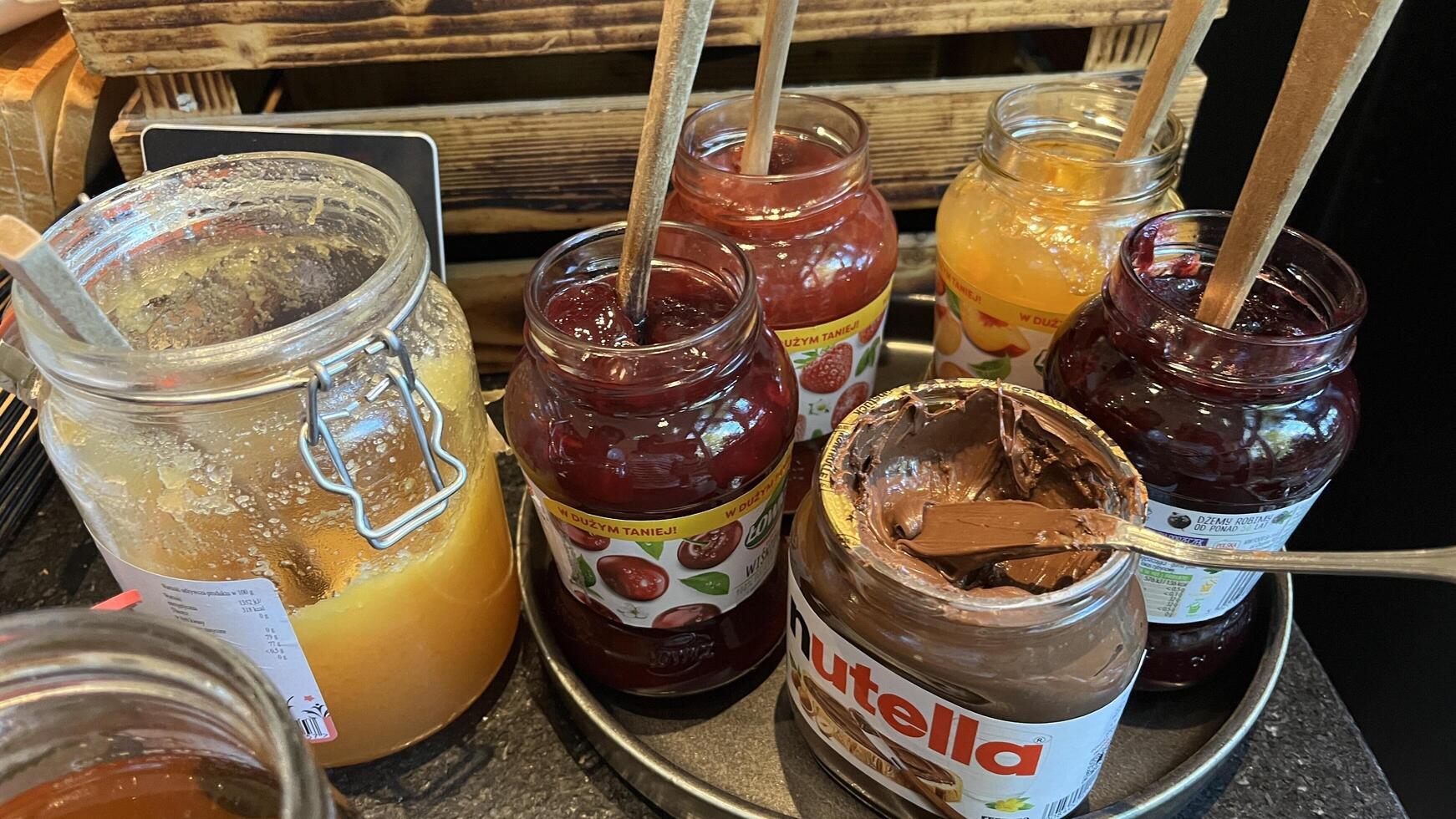 Warsaw, Poland. November 02, 2024. A variety of spreads and jams are displayed on a table, wooden spoons are placed in each jar. There's honey, cherry jam, apricot jam photo