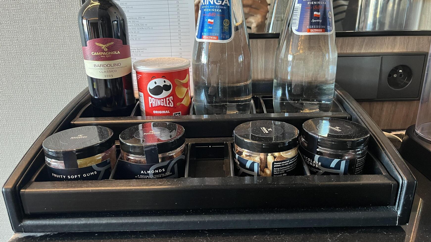 Warsaw, Poland. November 02, 2024. A hotel room minibar with various amenities. There's a sleek black coffee machine, a selection of bottled water, wine, coffee pods, and other snacks photo