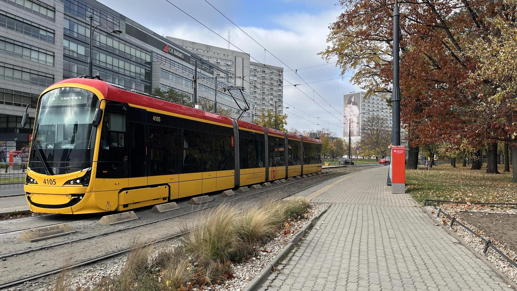 Warsaw, Poland. November 01, 2024. A modern yellow and red tram traveling along a track in a city in Warsaw. The tram stop near a sidewalk lined. Public transportation. photo