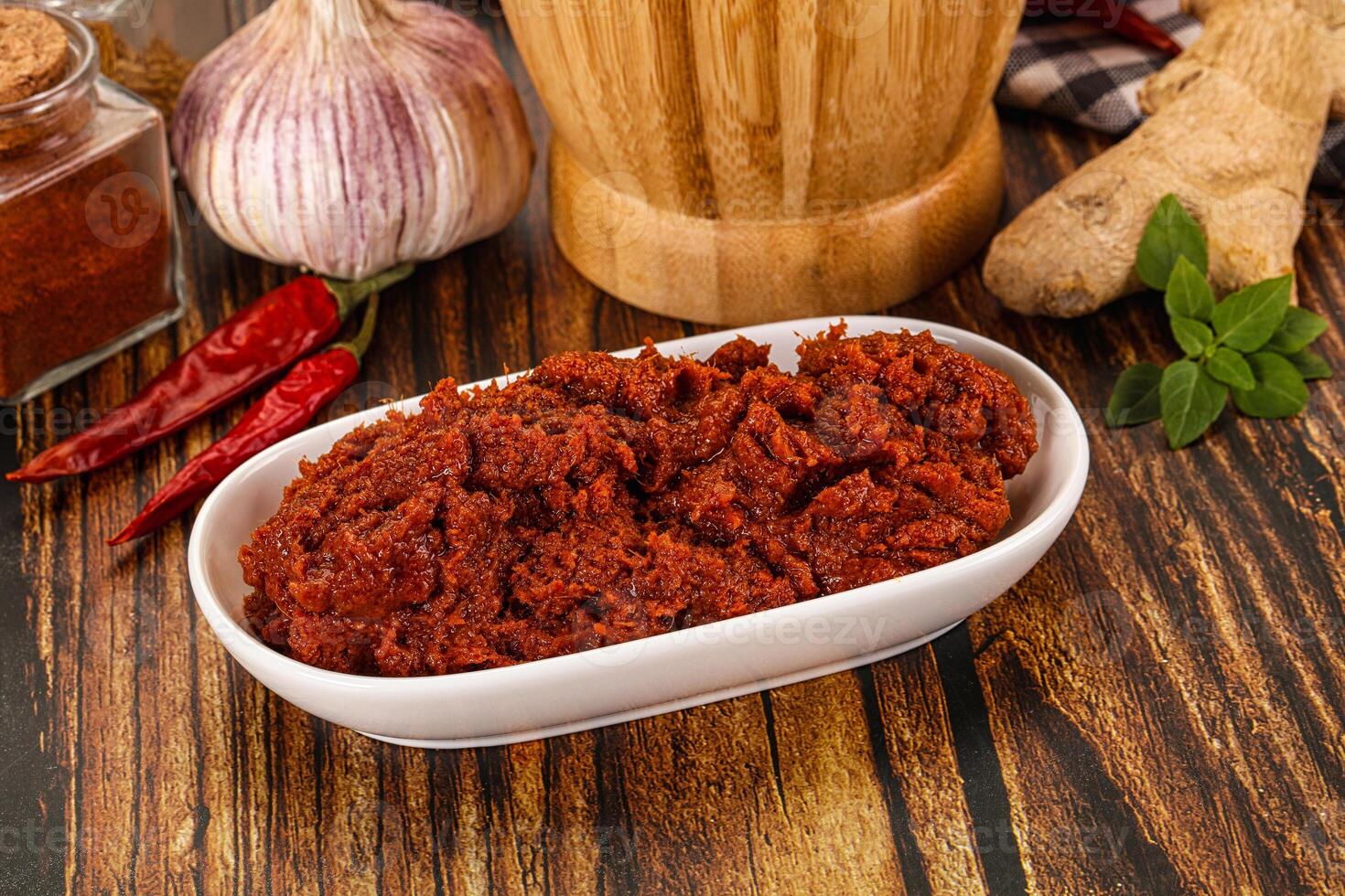 A bowl of chili powder next to a bottle of garlic paste photo