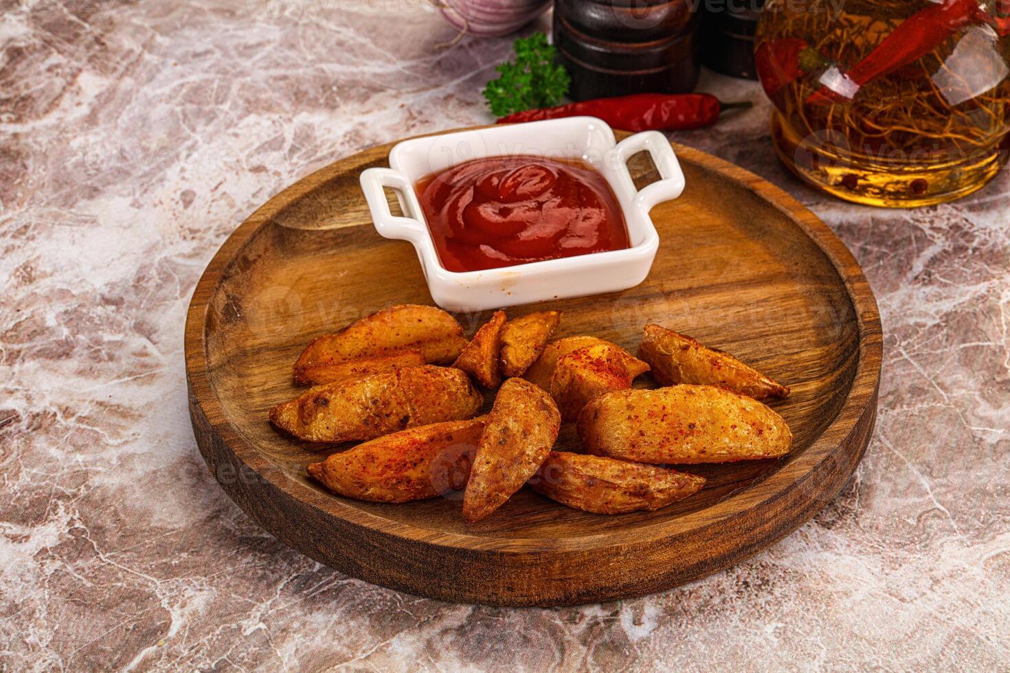 A wooden plate with some potatoes and ketchup photo