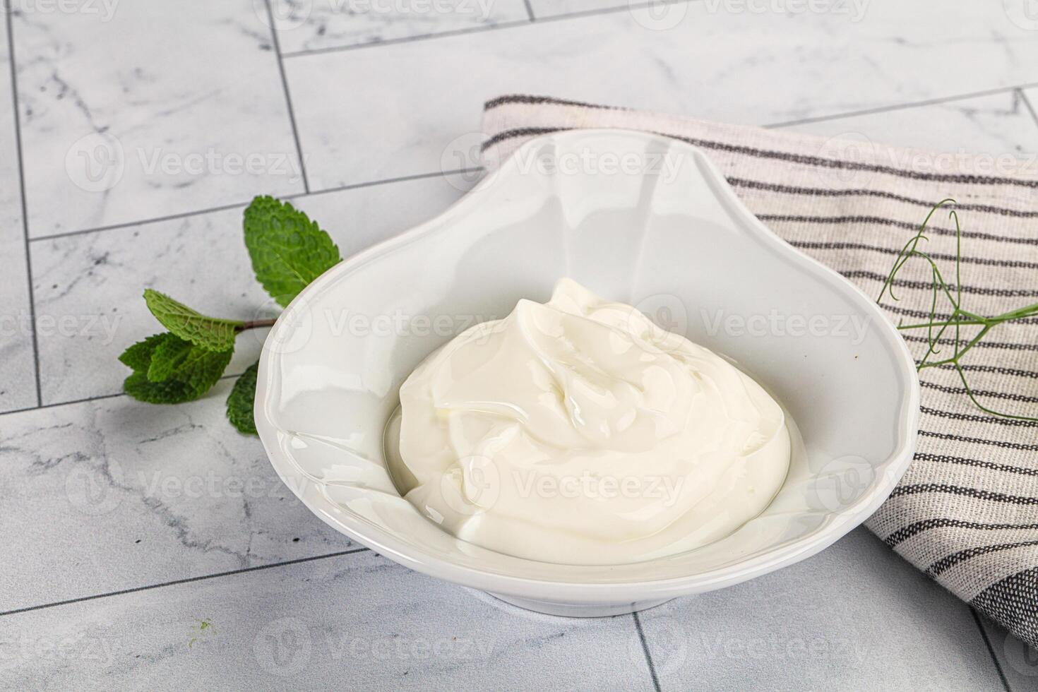 A bowl of yogurt with a spoon and a sprig of mint photo