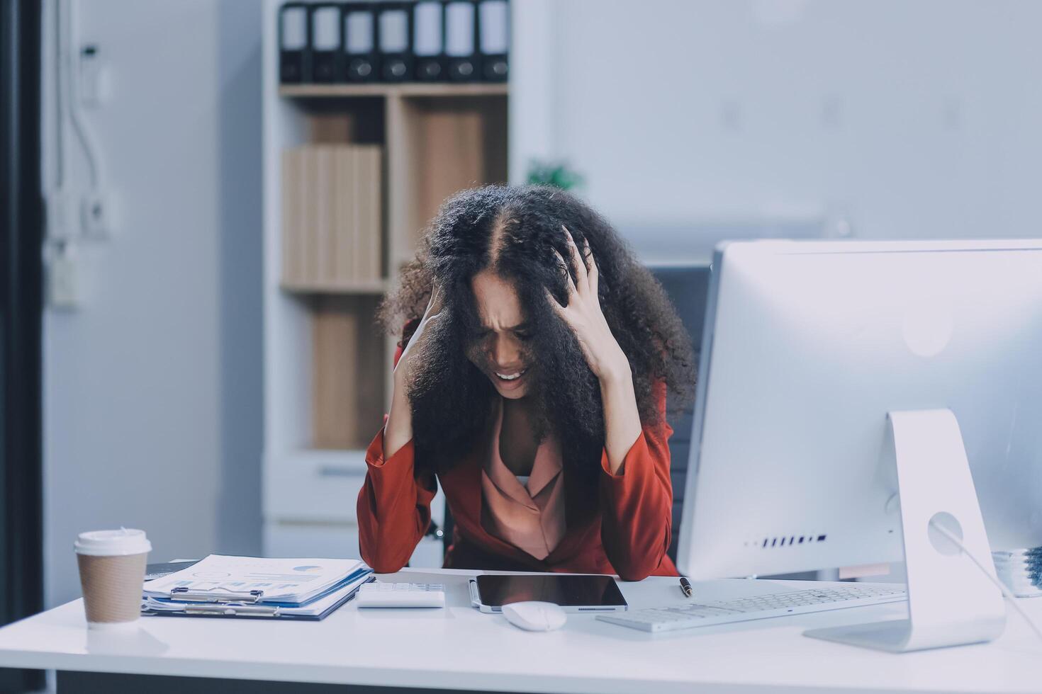 A woman is sitting at her desk with her head in her hands photo