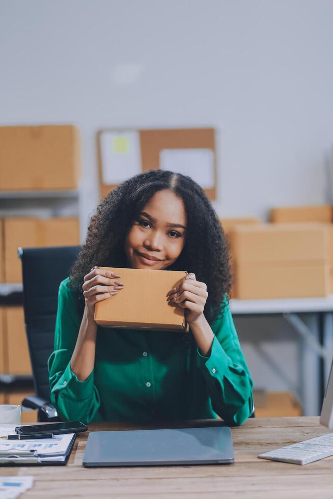 A woman is holding a box in front of her laptop photo