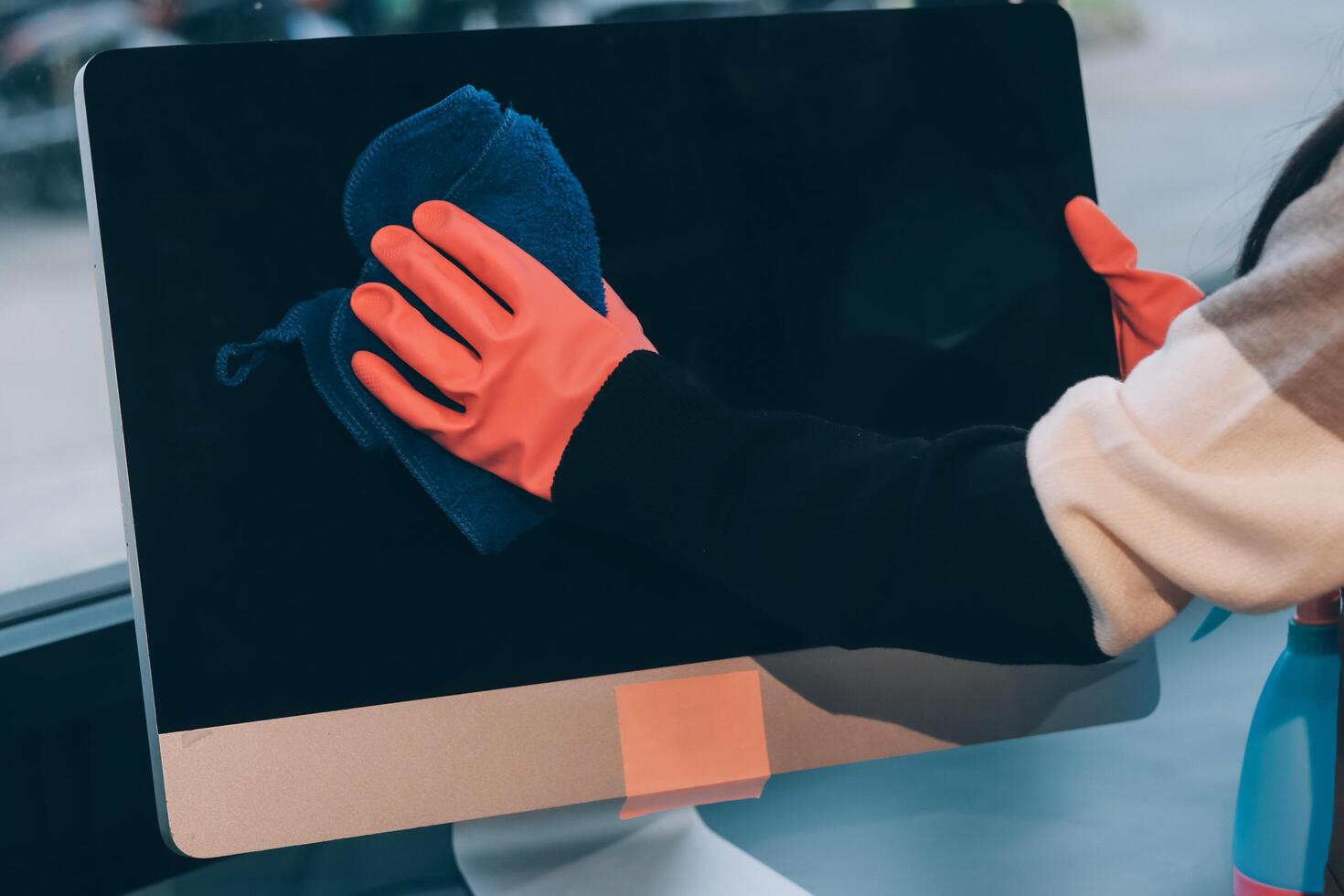 A person cleaning a computer monitor with a cloth photo