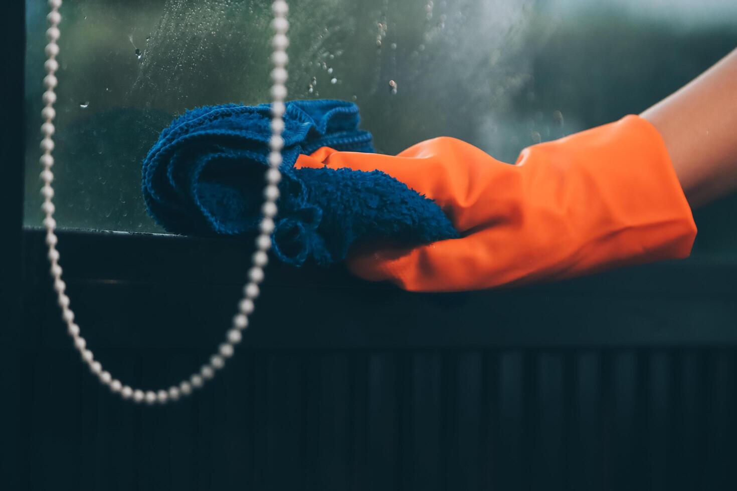 A person wearing an orange glove cleaning a window photo