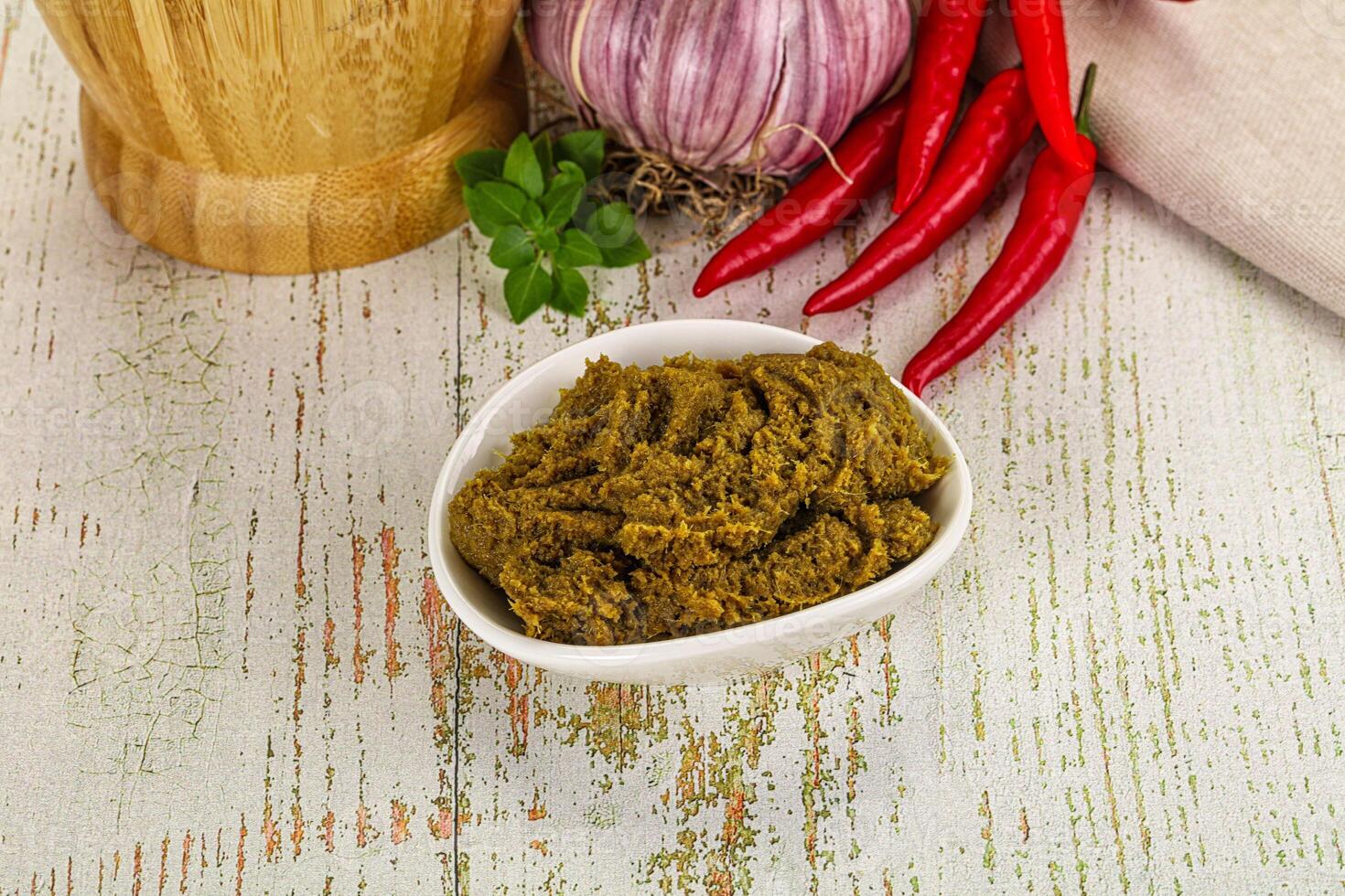 A bowl of green sauce next to a pepper and a red onion photo