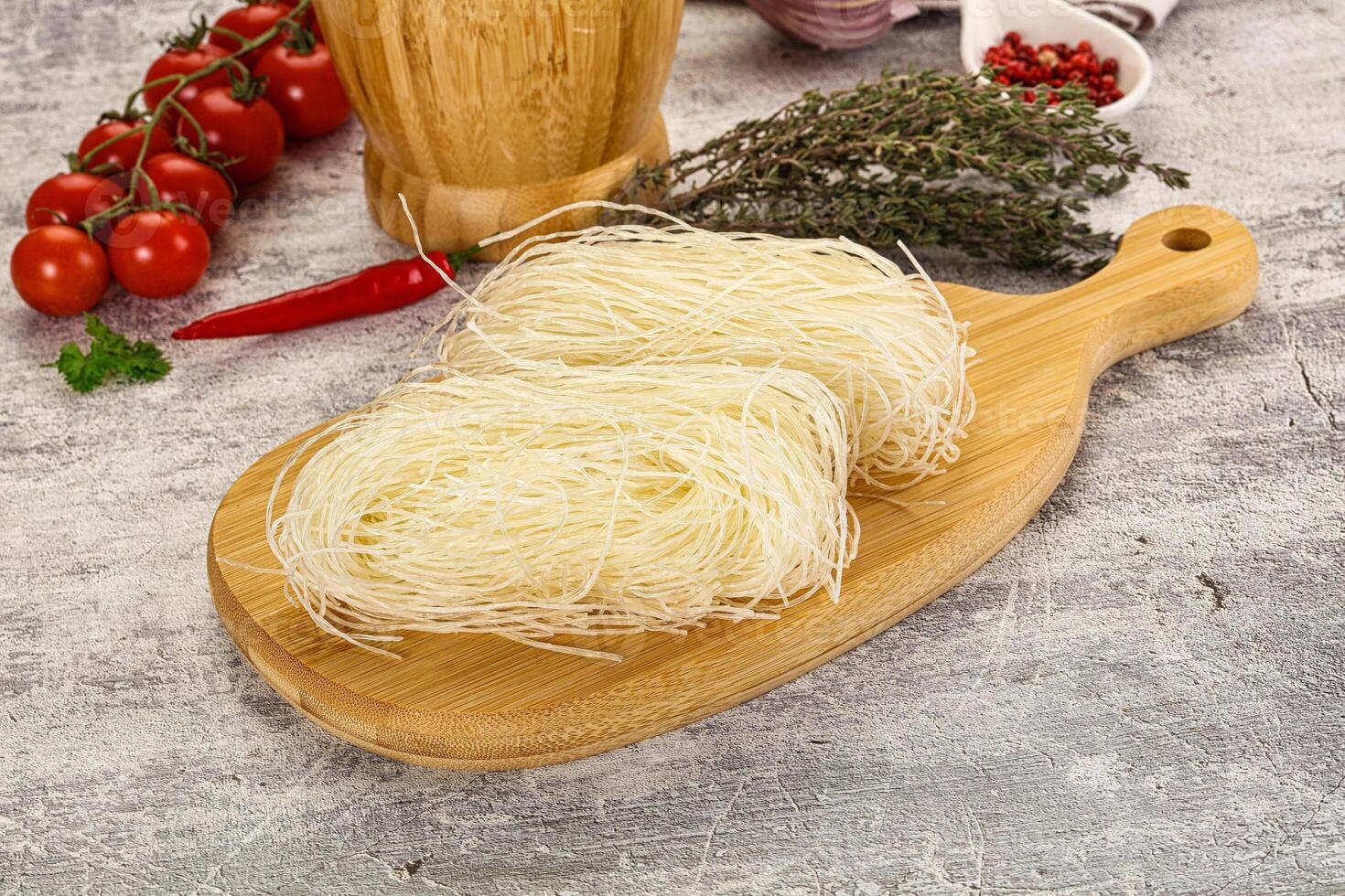 A wooden cutting board with noodles and tomatoes photo