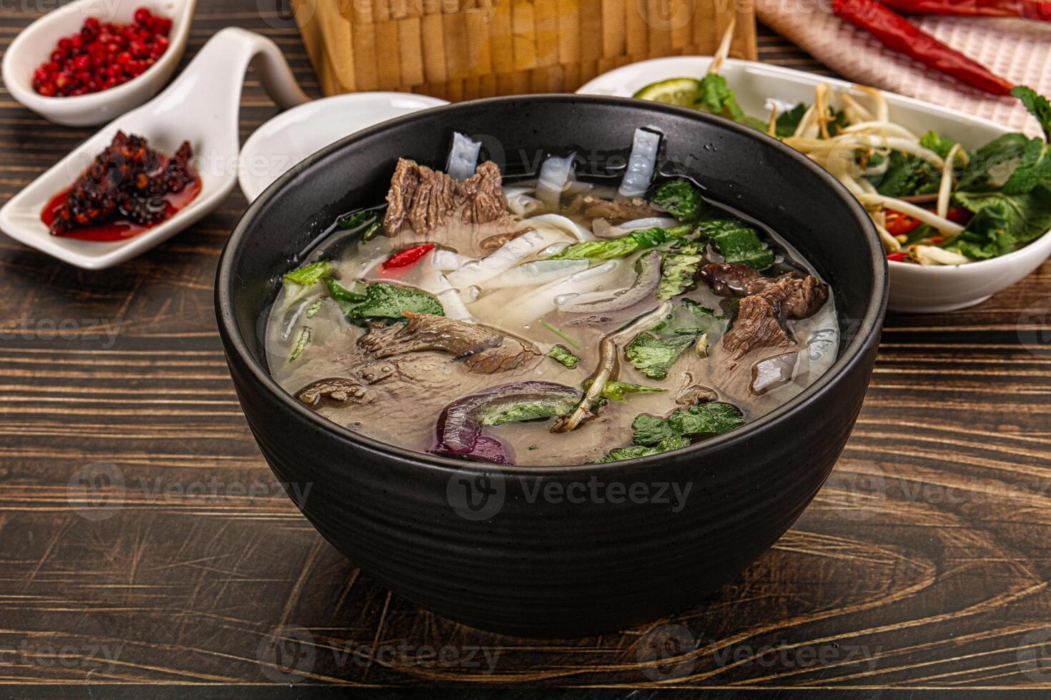 A bowl of soup with meat and vegetables on a table photo