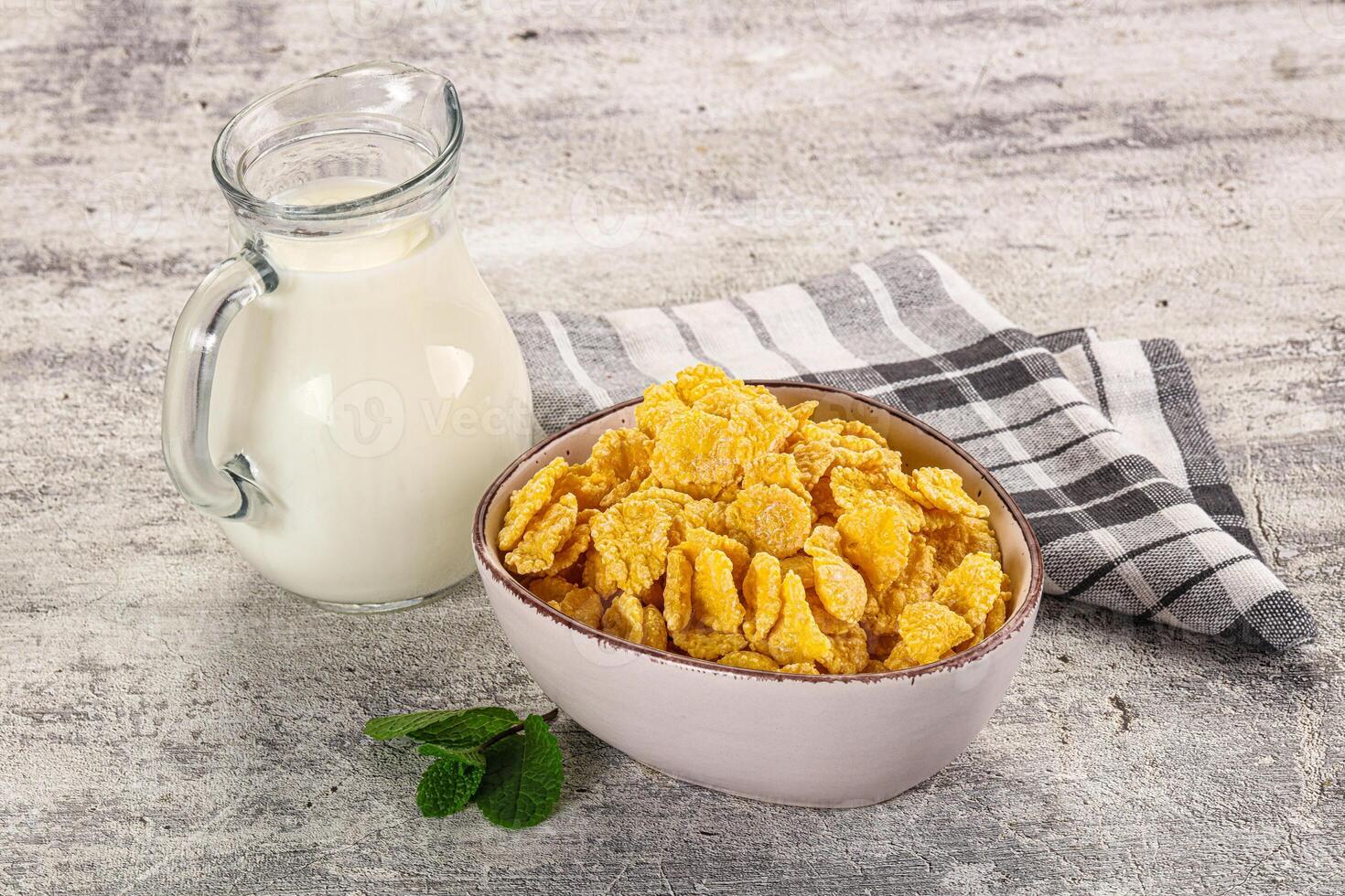 A bowl of corn flakes and a jug of milk photo