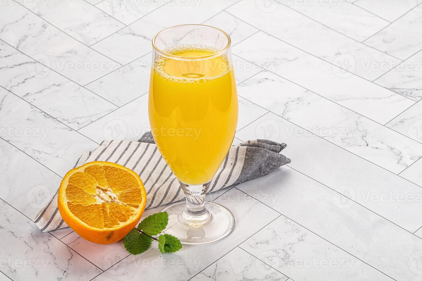 Orange juice in a glass on a marble countertop photo