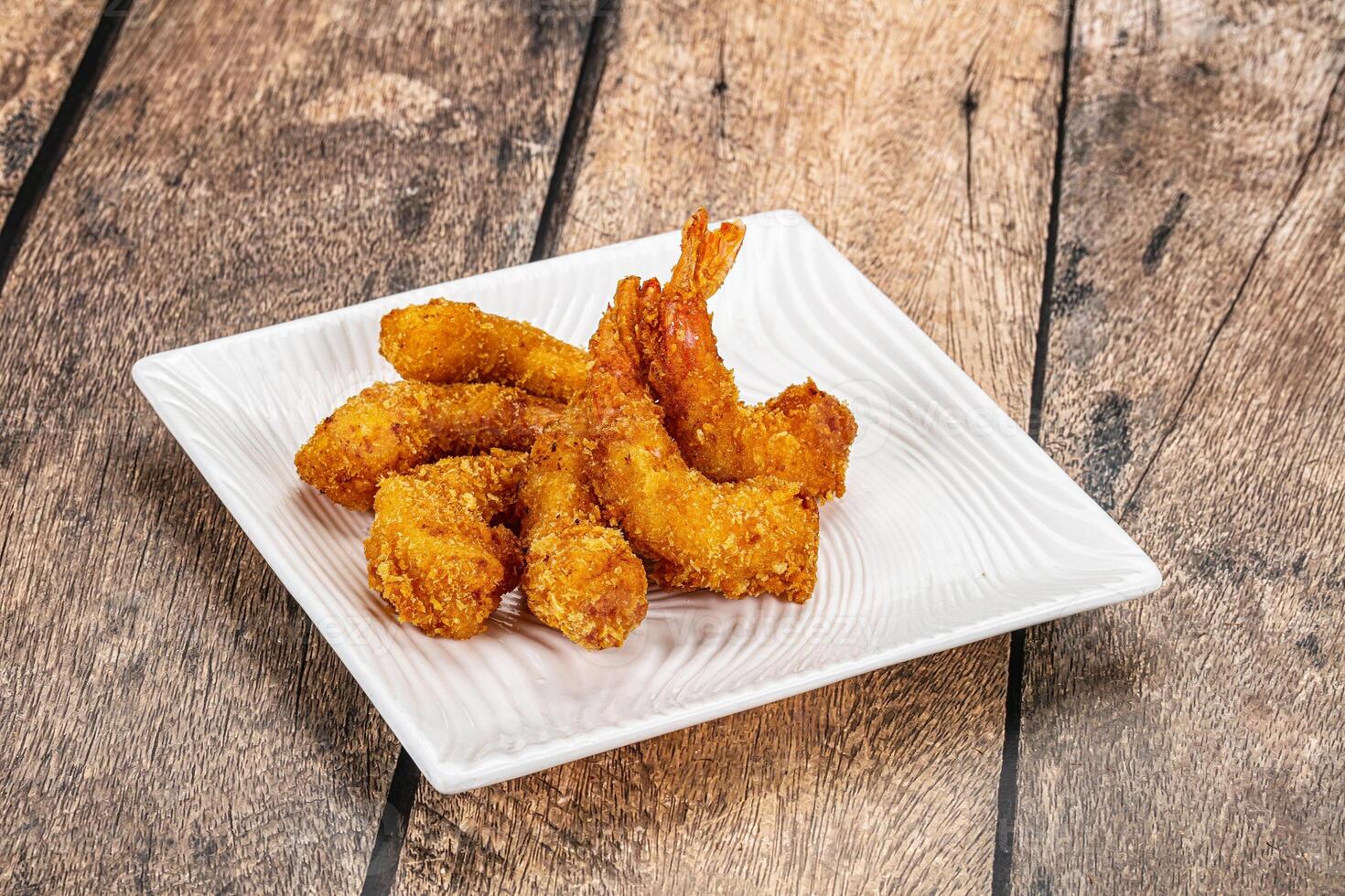 Fried shrimp on a white plate on a wooden table photo
