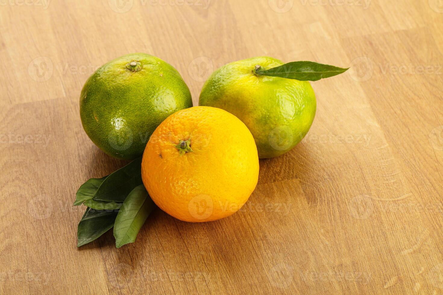 Three oranges and one lemon on a wooden table photo
