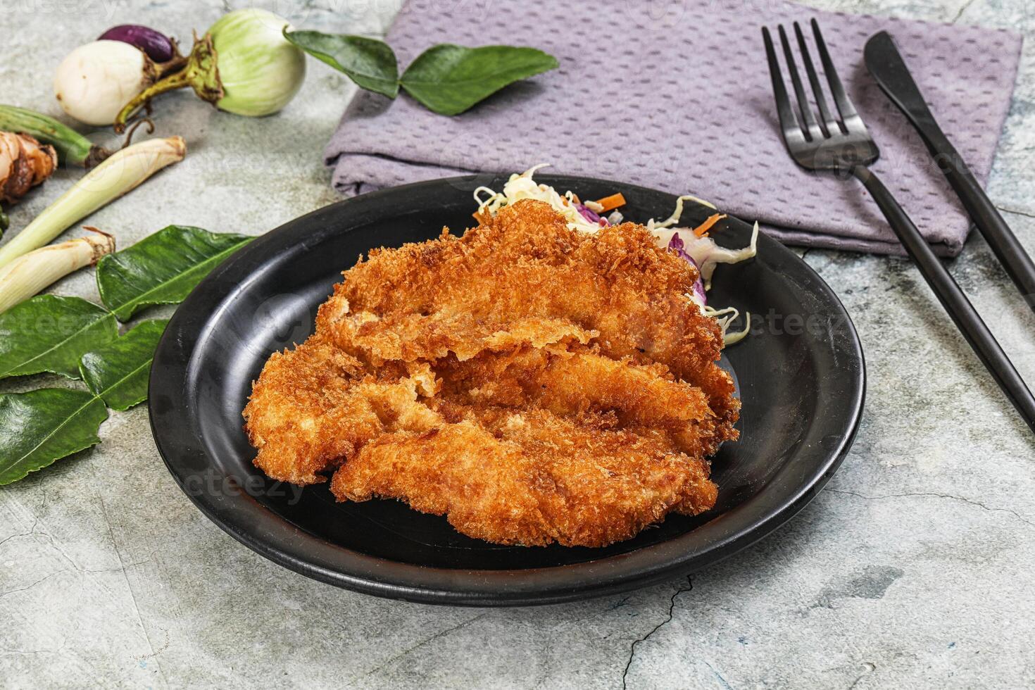 Fried chicken on a black plate with a napkin and fork photo