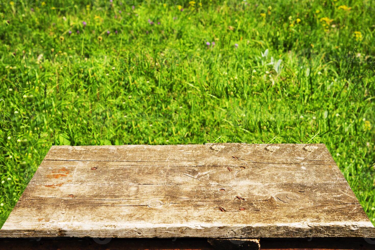 empty old brown table on green grass background. photo