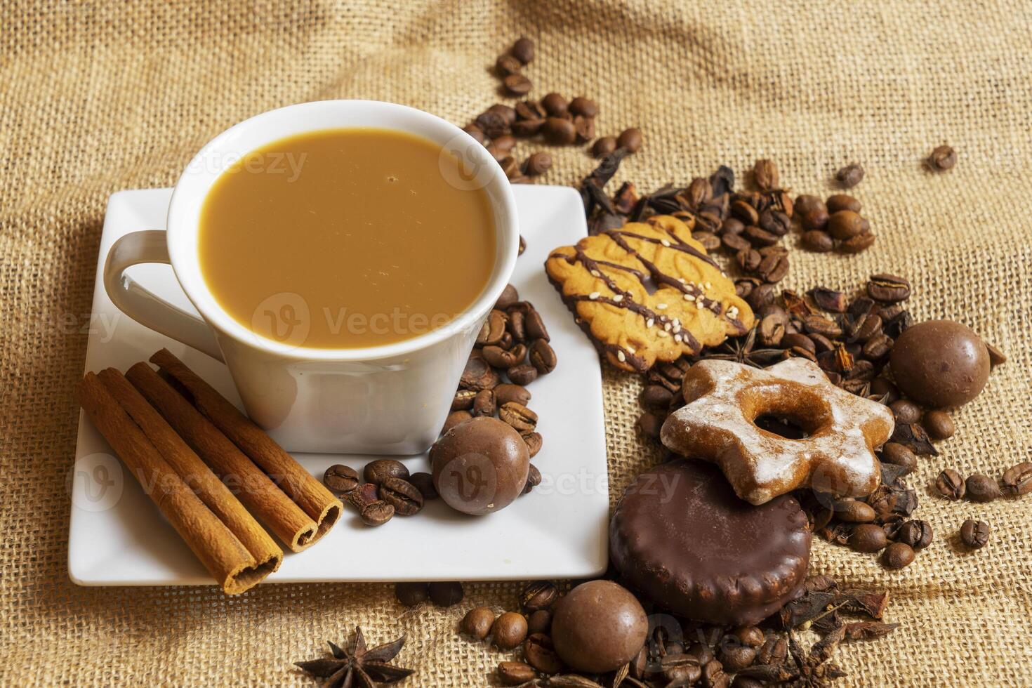 A white cup with a saucer and coffee and coffee beans on a brown cloth background. photo