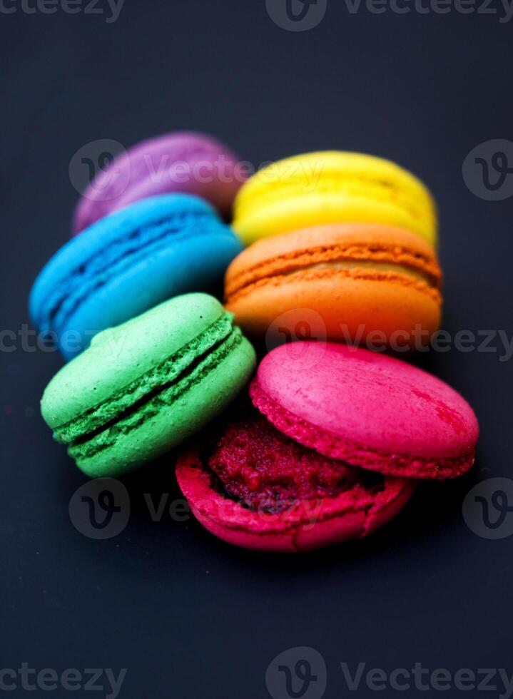 Sweet and colorful french macaroons or macaron on black background. photo