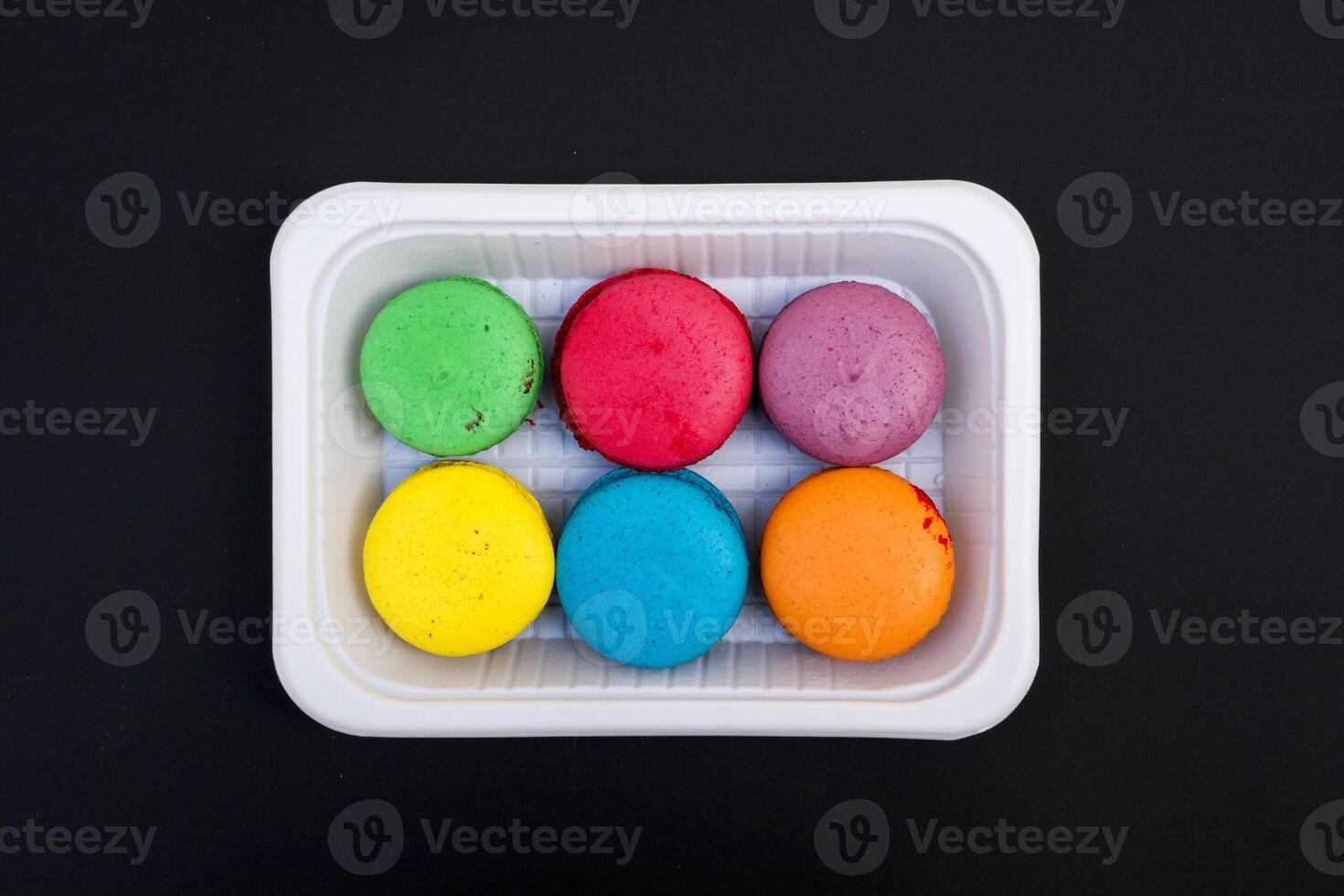 colored macaroons on a white plate on a black background photo