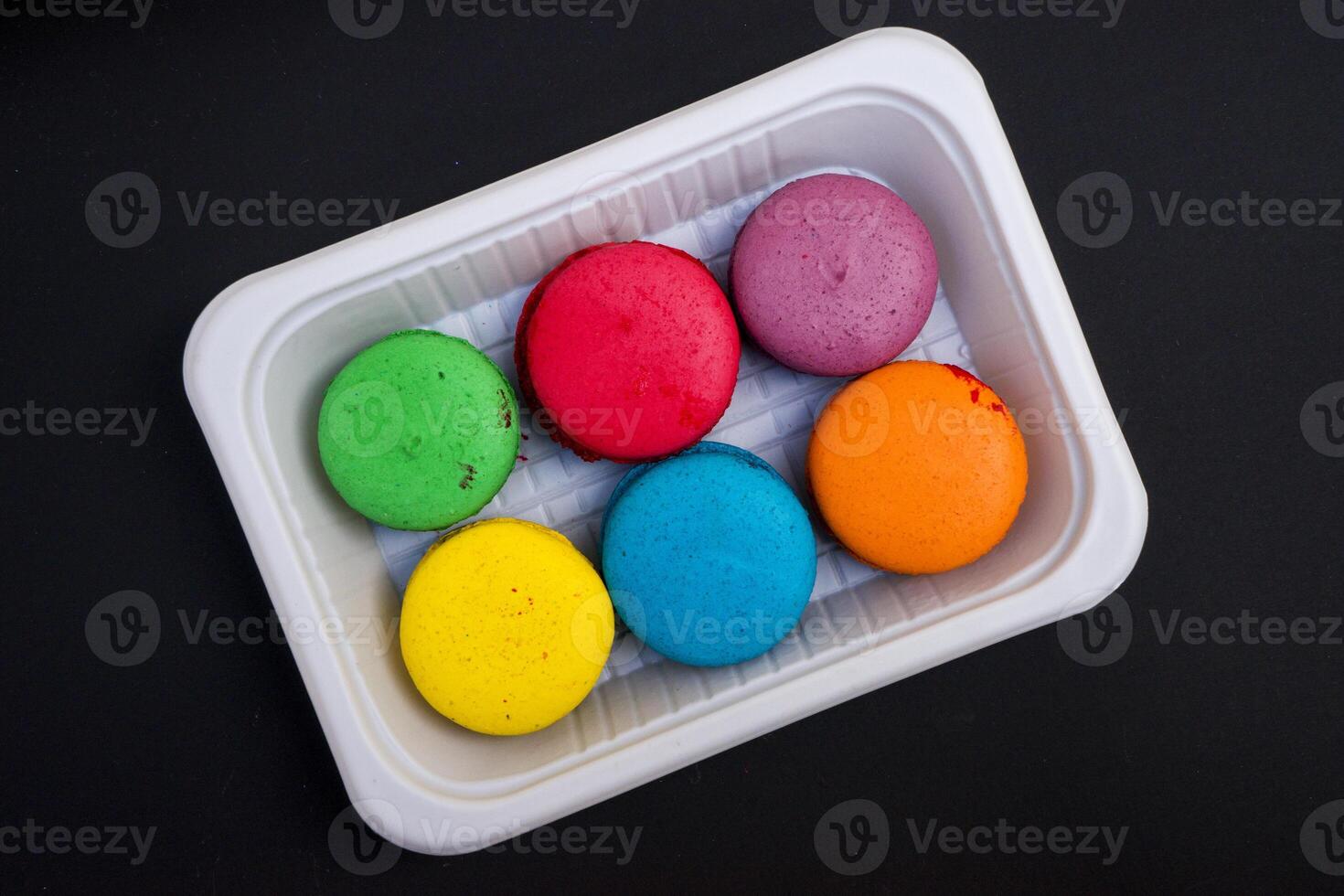 colored macaroons on a white plate on a black background photo