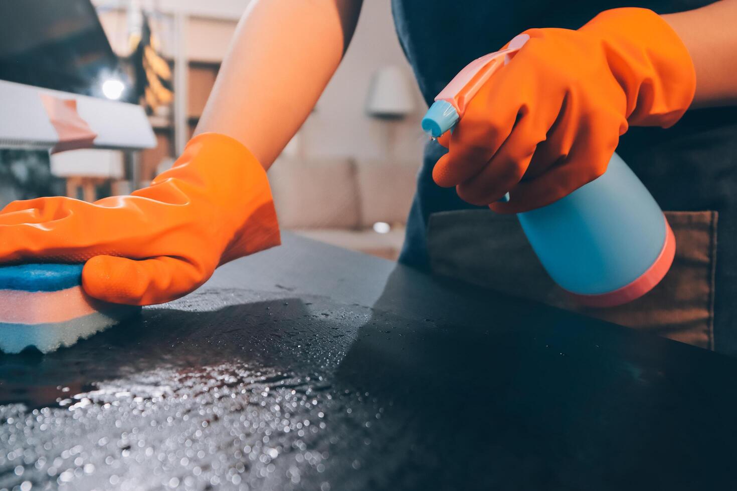 A person in an orange glove cleaning a table photo
