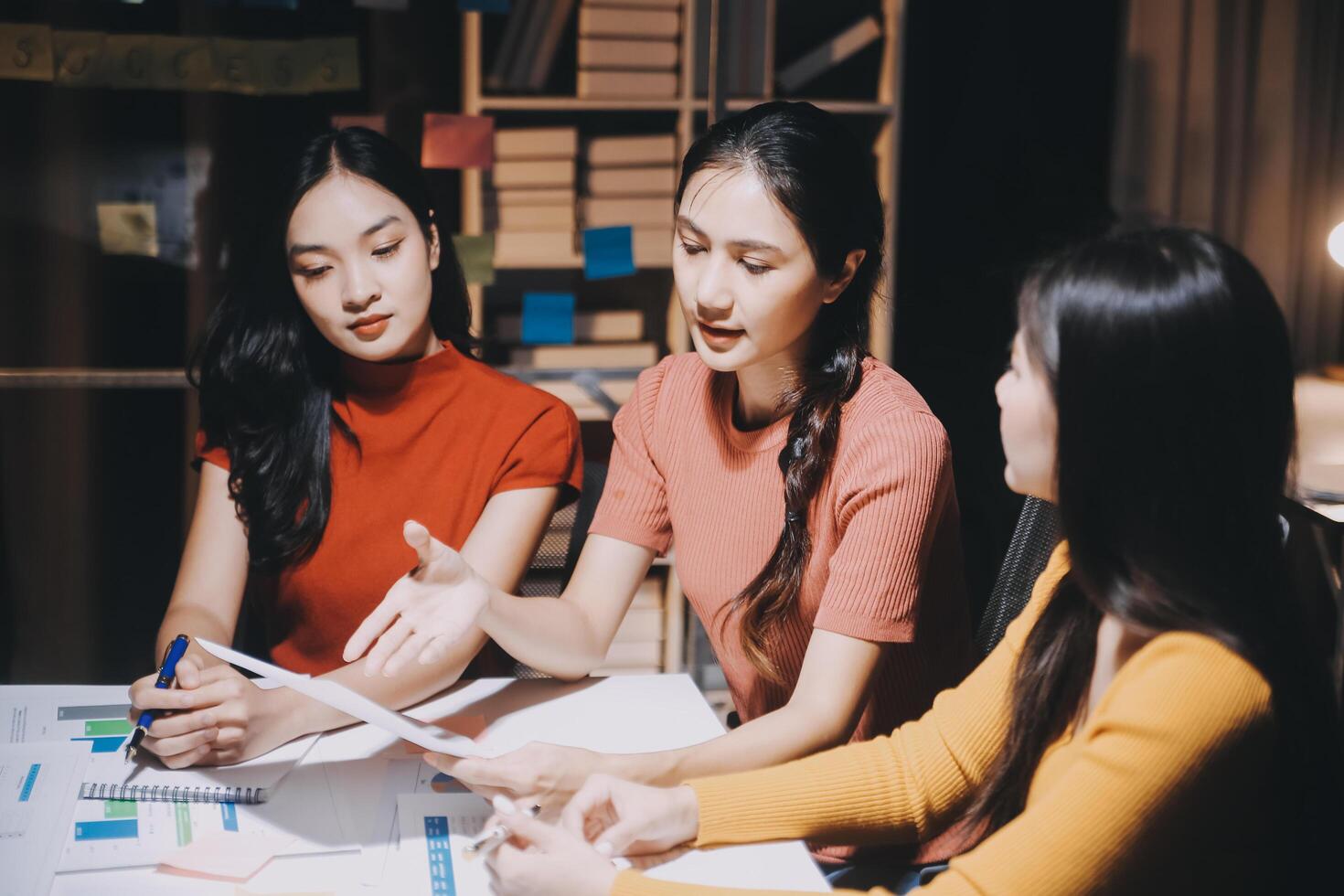 Three women sitting at a table with papers and pens photo