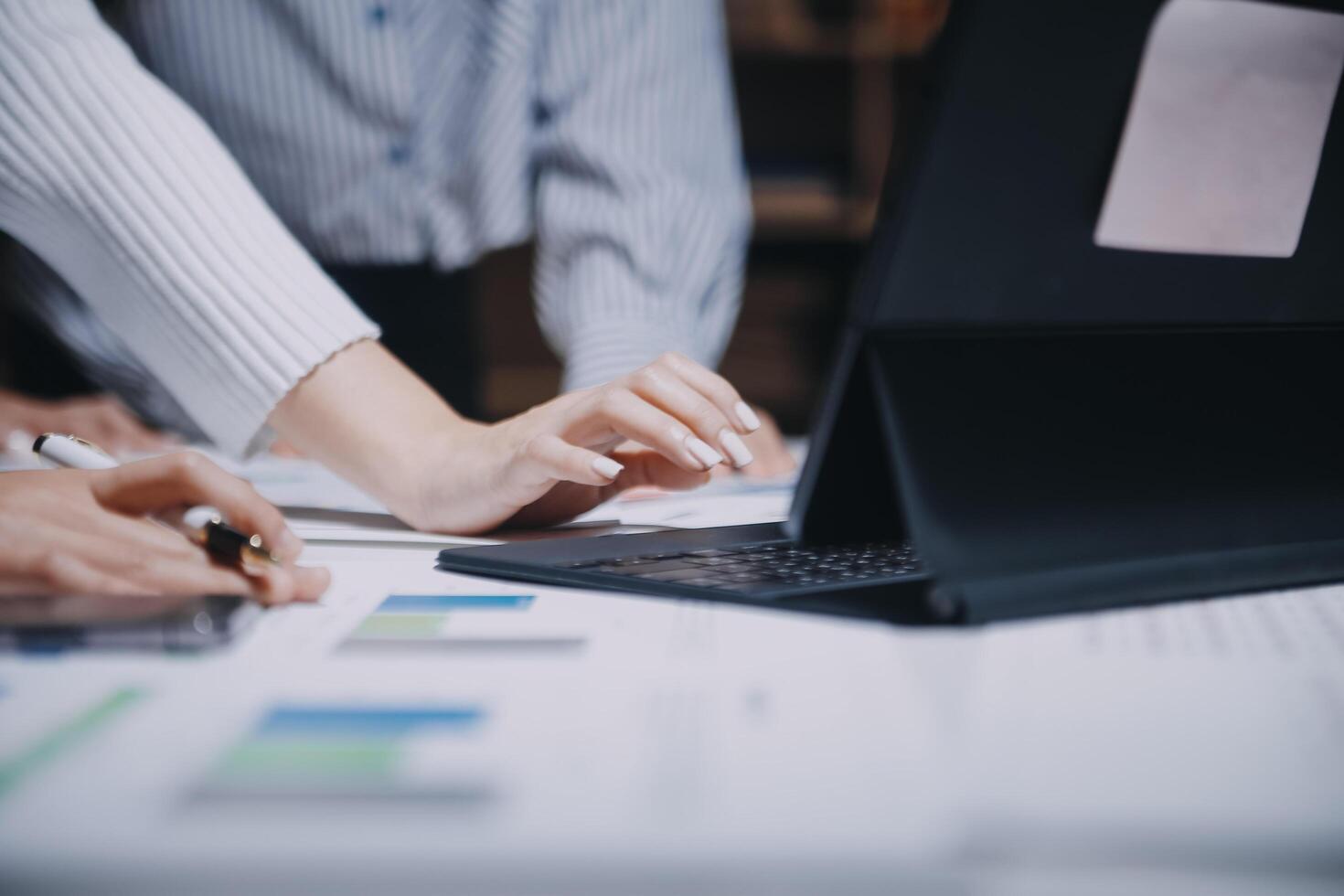 Business people working on a laptop with papers and graphs photo