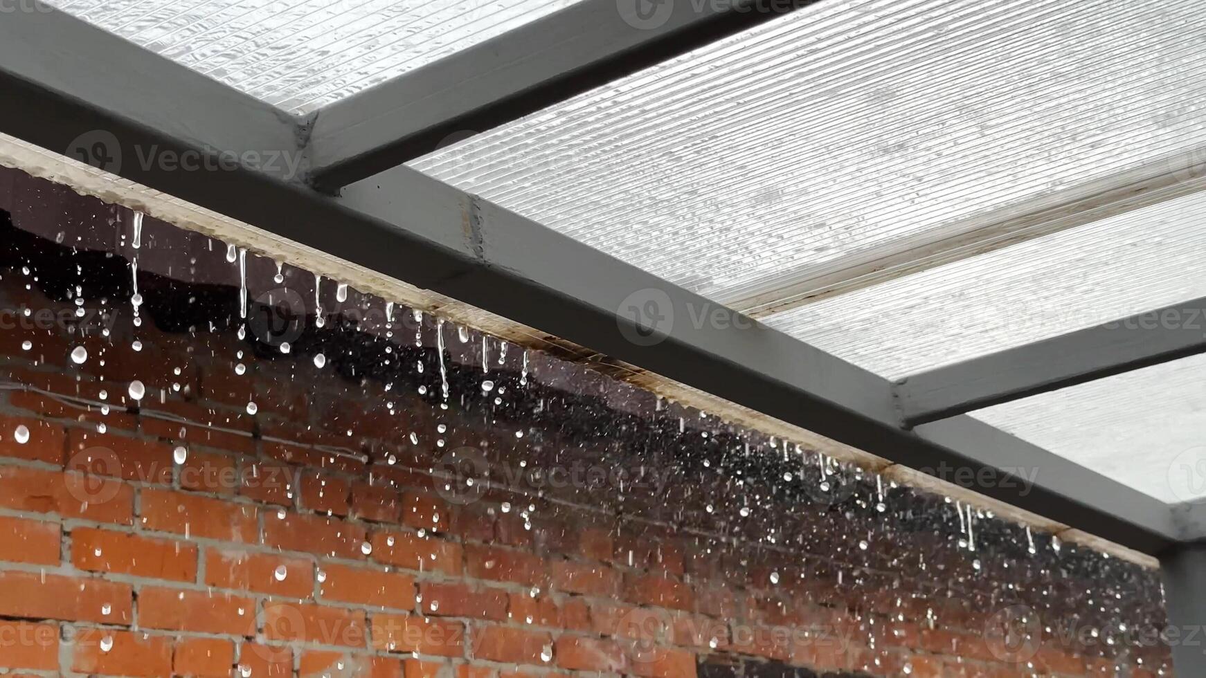 Heavy rain drumming on the transparent plexiglass roof. Beautiful rainy scene on summer day. Concept of tranquility nature scene. Close up Slow motion photo