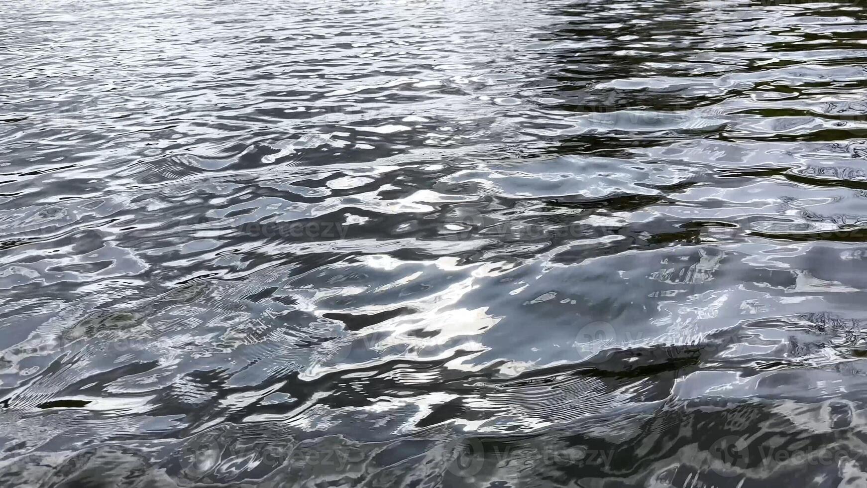 Scenery surface of pond illuminated by sun at summertime. Calm view on sea with small waves at sunny day. Beautiful summer nature landscape. Concept of tranquility scene. Slow motion photo