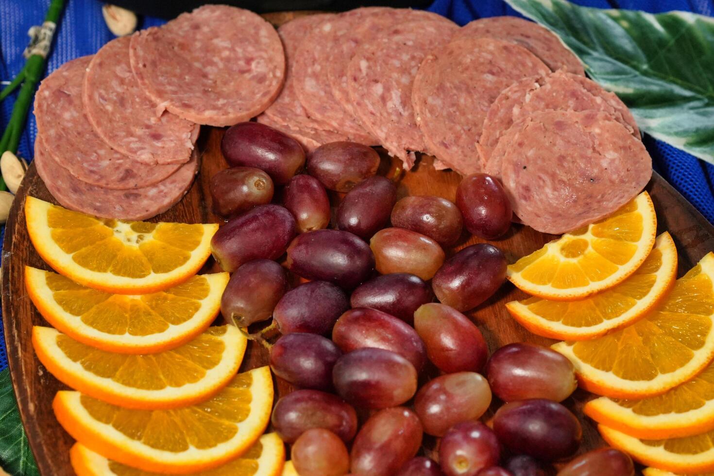 a platter of sausage, grapes and sliced oranges photo