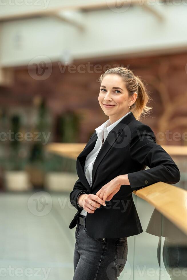 Businesswoman leaning on railing in modern office building photo